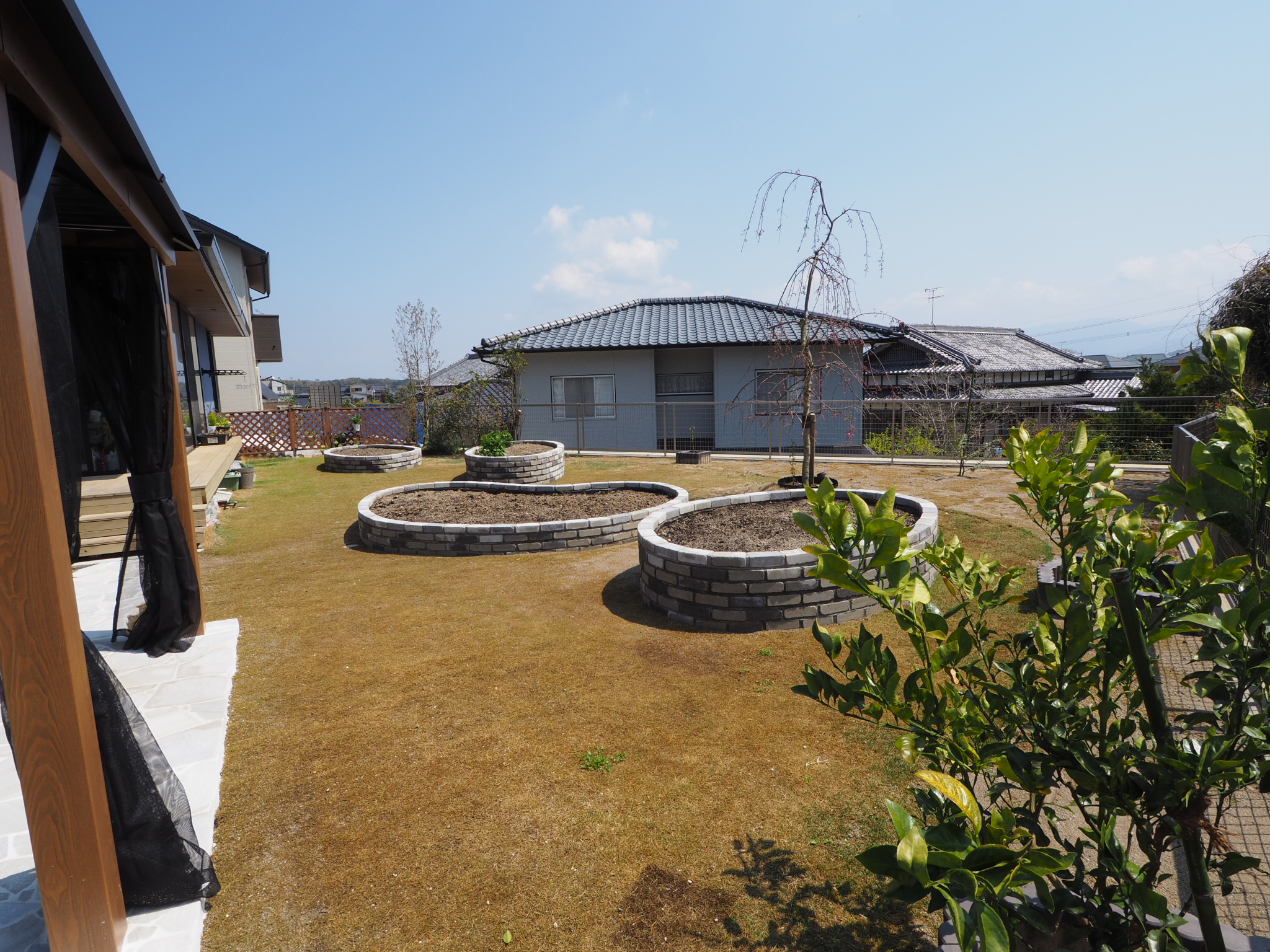 ガゼボと白い石畳のテラスのあるお庭の全景